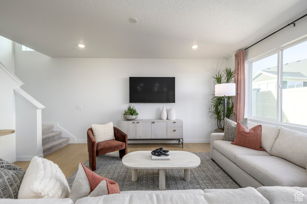 Living room with wood finished floors, stairs, baseboards, and recessed lighting