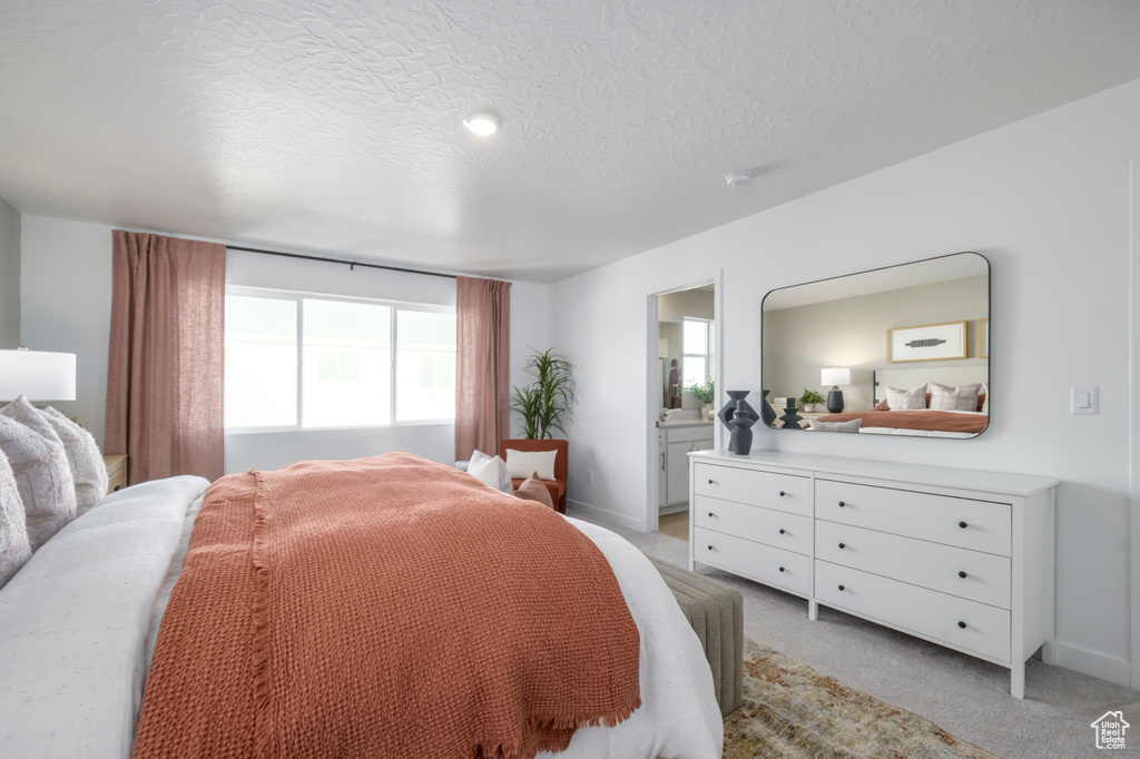 Bedroom featuring light colored carpet, a textured ceiling, connected bathroom, and baseboards