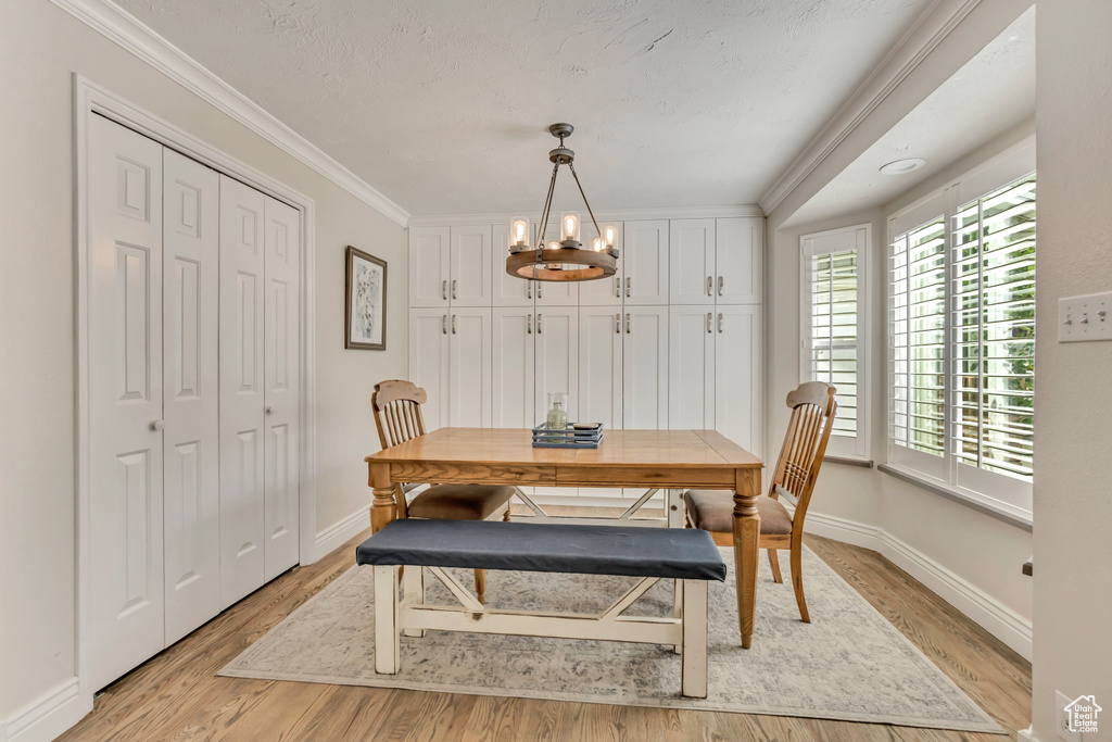 Dining space featuring a chandelier, light wood-style flooring, crown molding, and baseboards