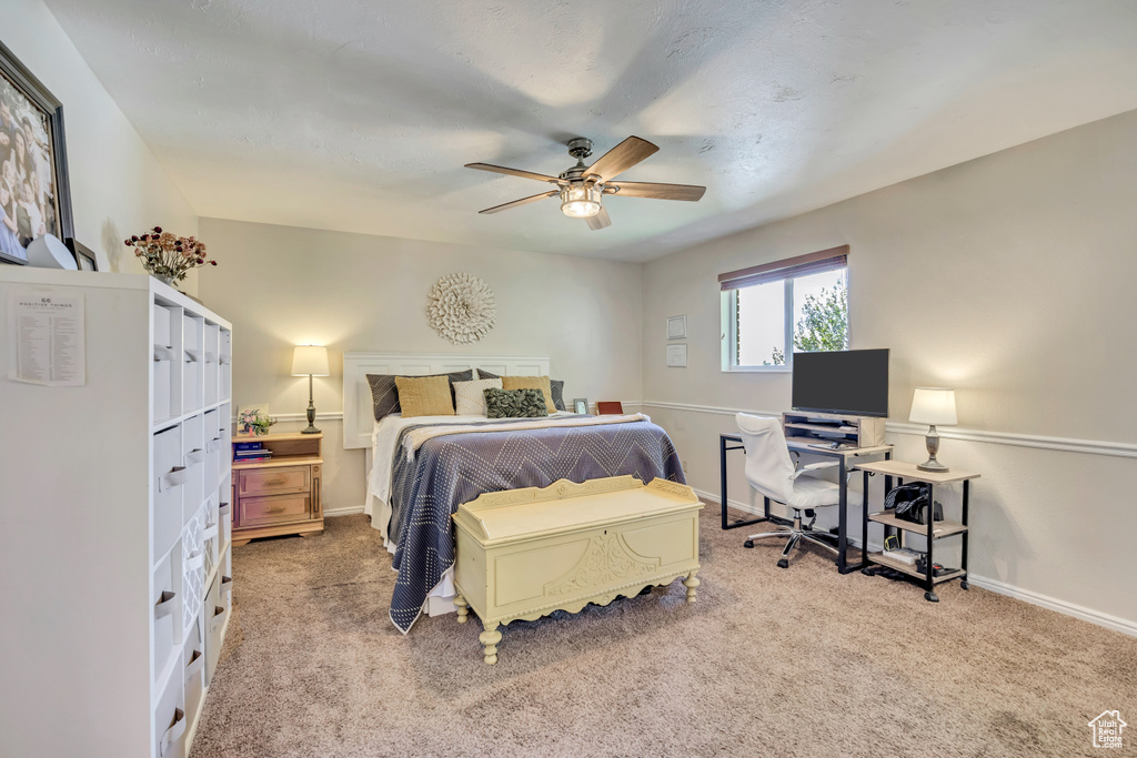 Bedroom with light colored carpet, baseboards, and ceiling fan