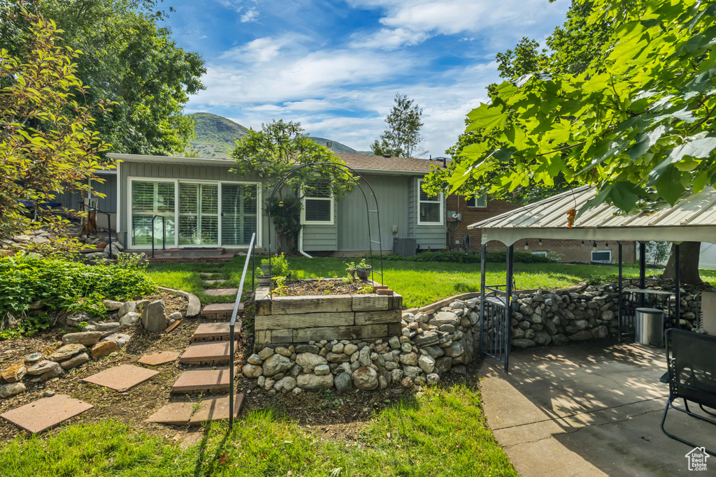 View of front of house featuring board and batten siding, a patio area, a gazebo, cooling unit, and a mountain view