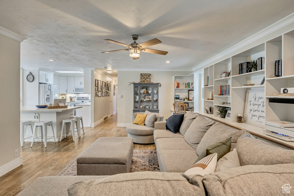 Living area with crown molding, ceiling fan, light wood-type flooring, baseboards, and recessed lighting