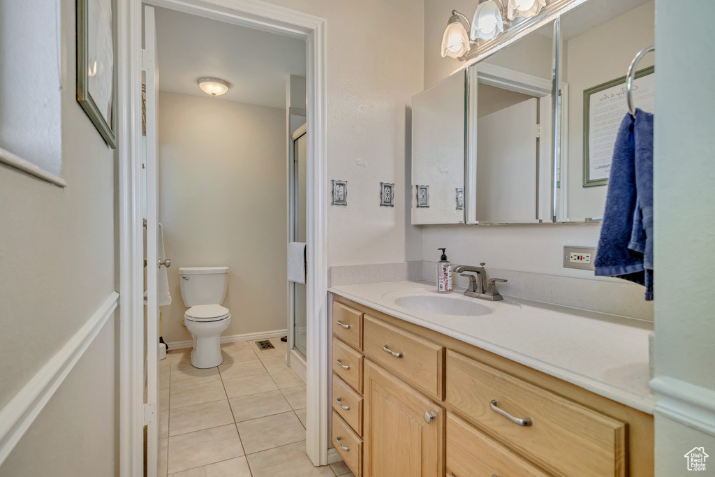 Bathroom with toilet, tile patterned floors, vanity, and a stall shower