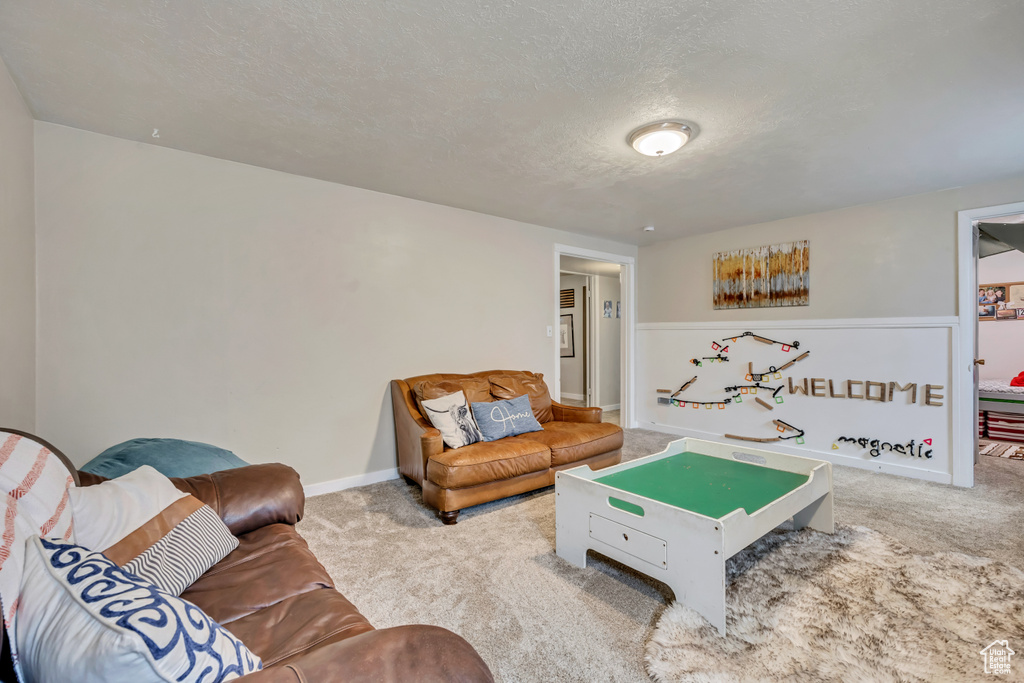 Living area featuring carpet flooring, a textured ceiling, and baseboards