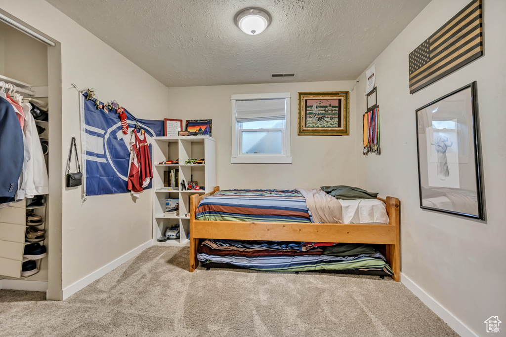 Bedroom with carpet floors, a textured ceiling, and baseboards