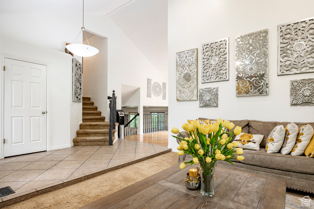 Living room featuring high vaulted ceiling, stairway, and baseboards