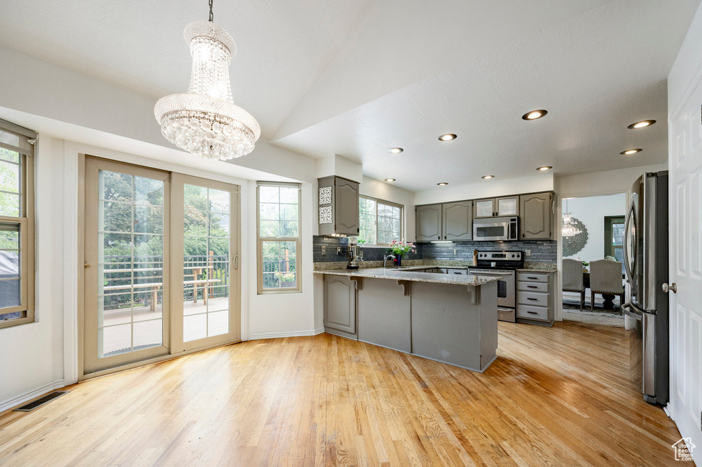 Kitchen featuring appliances with stainless steel finishes, gray cabinets, healthy amount of natural light, a peninsula, and recessed lighting