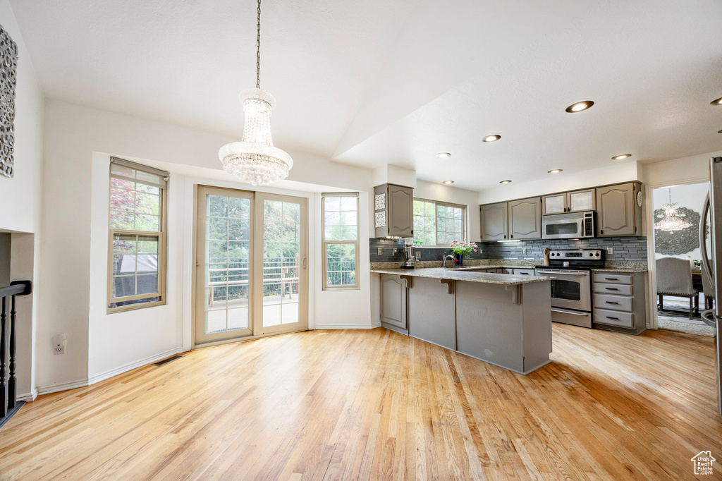 Kitchen with appliances with stainless steel finishes, gray cabinetry, light wood-style floors, a chandelier, and recessed lighting