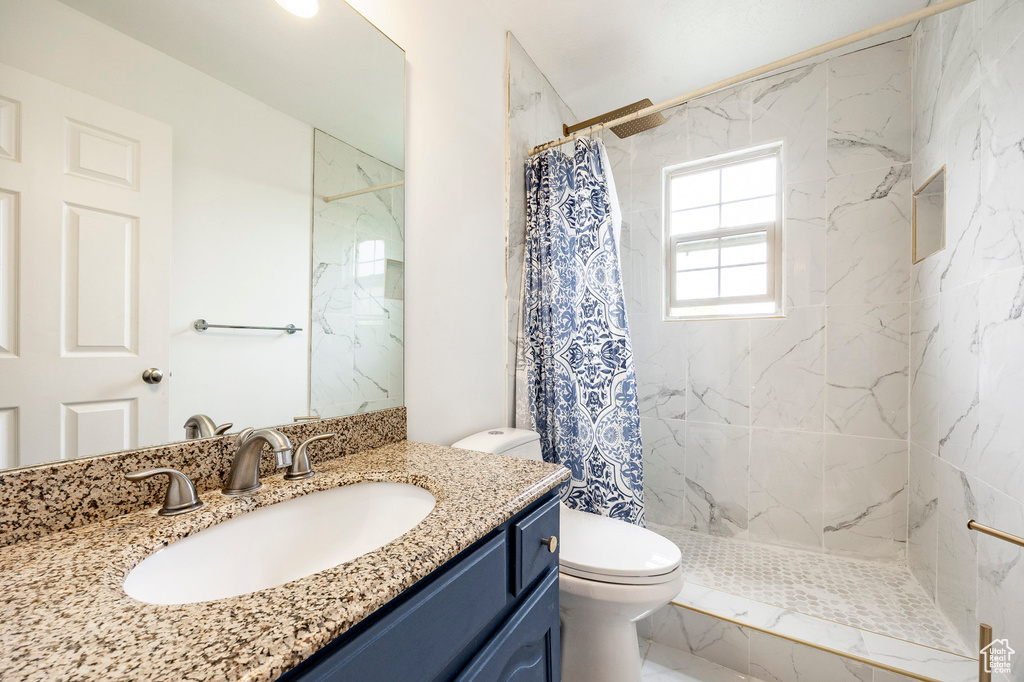 Bathroom with toilet, curtained shower, and vanity