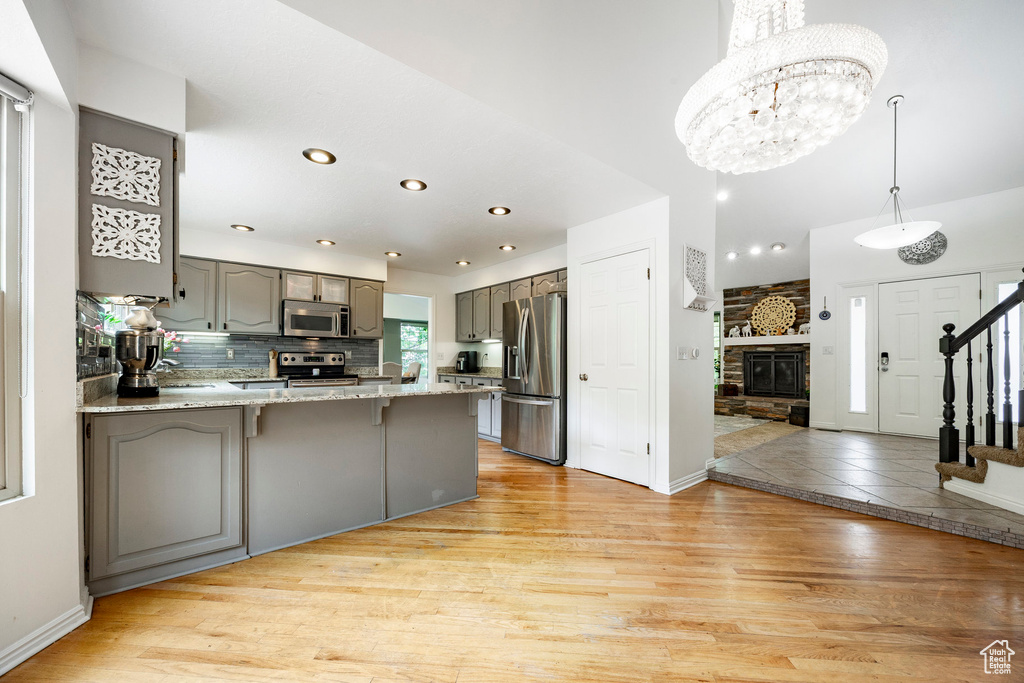 Kitchen featuring stainless steel appliances, gray cabinetry, a peninsula, light wood-style floors, and recessed lighting