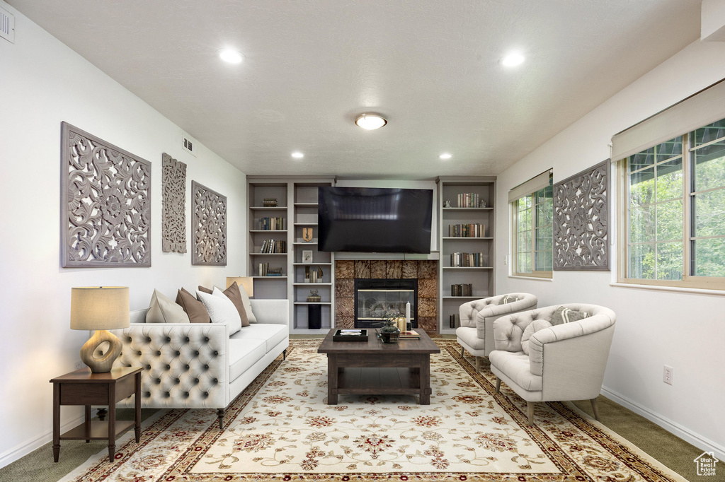 Living area featuring baseboards, recessed lighting, a glass covered fireplace, built in shelves, and carpet flooring