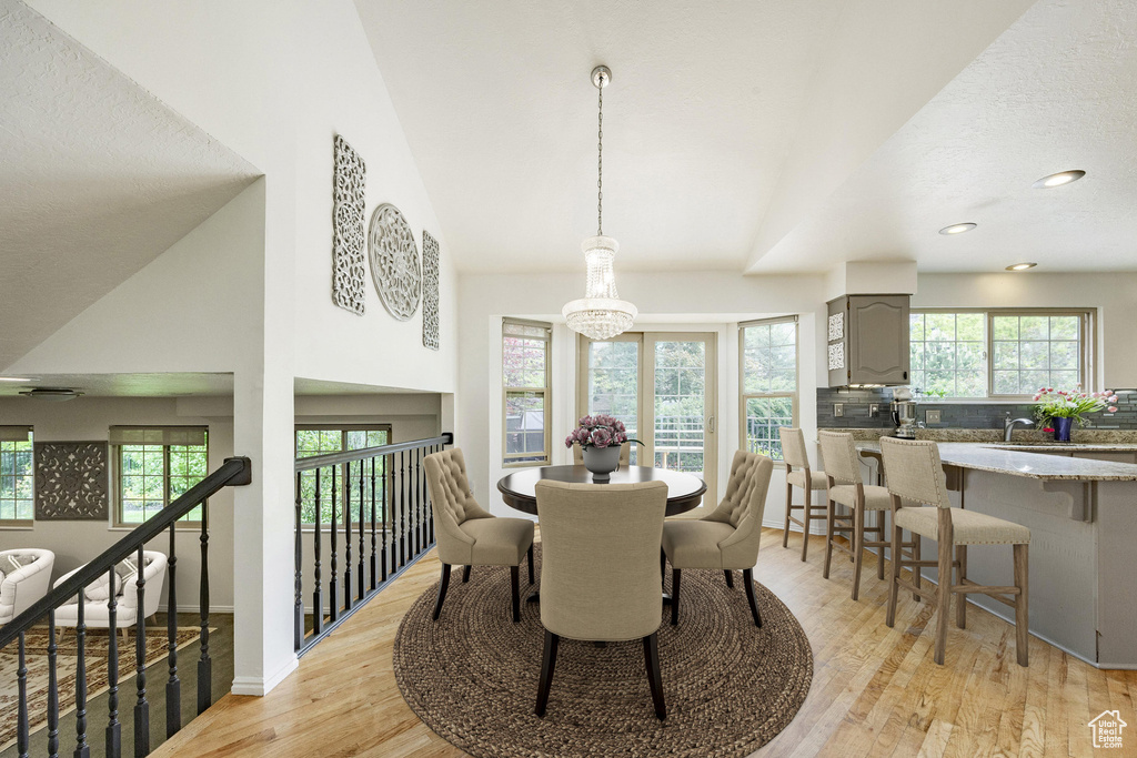 Dining area featuring healthy amount of natural light, light wood finished floors, a chandelier, recessed lighting, and baseboards