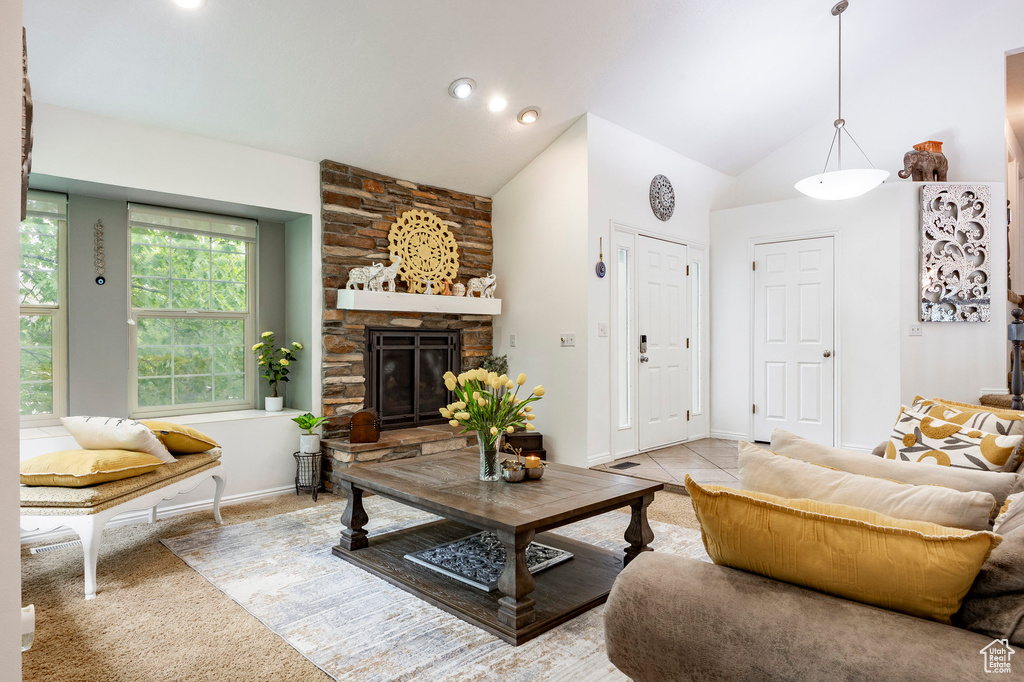 Carpeted living room with a stone fireplace, high vaulted ceiling, and baseboards