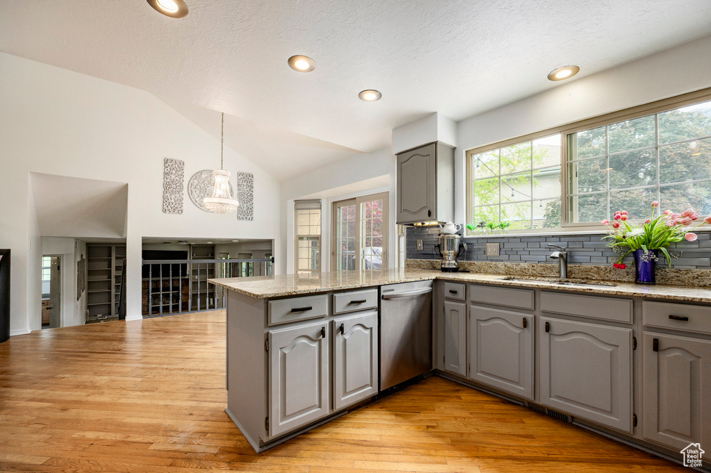 Kitchen with dishwasher, gray cabinetry, a peninsula, a sink, and light wood-type flooring
