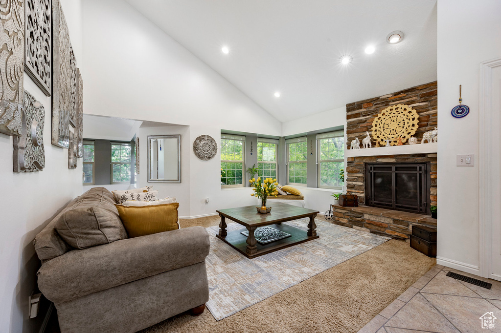 Tiled living room featuring high vaulted ceiling, recessed lighting, baseboards, and a stone fireplace