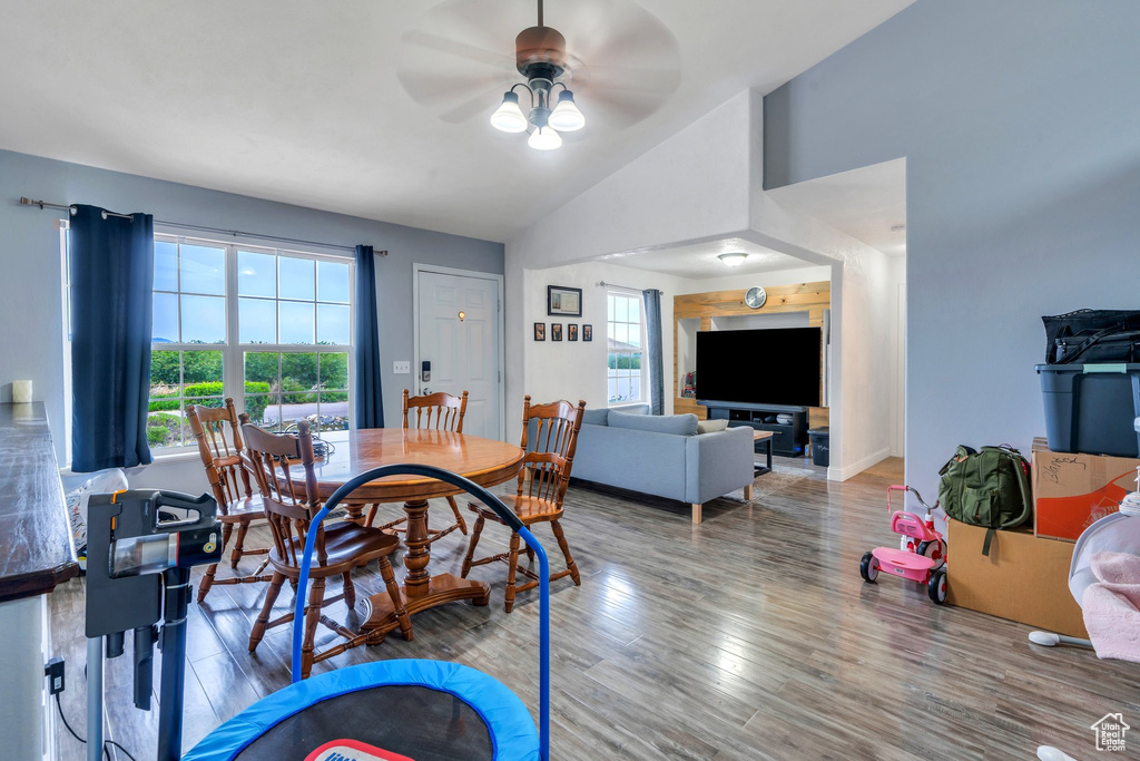 Dining room with ceiling fan, wood finished floors, and vaulted ceiling