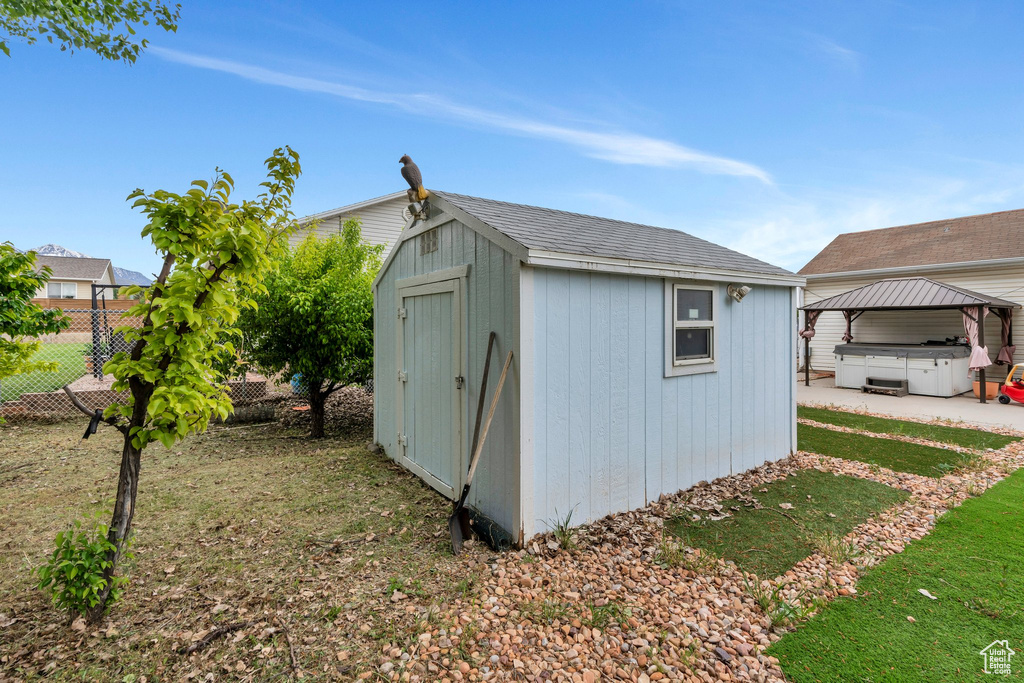 View of shed featuring fence, a covered hot tub, and a gazebo