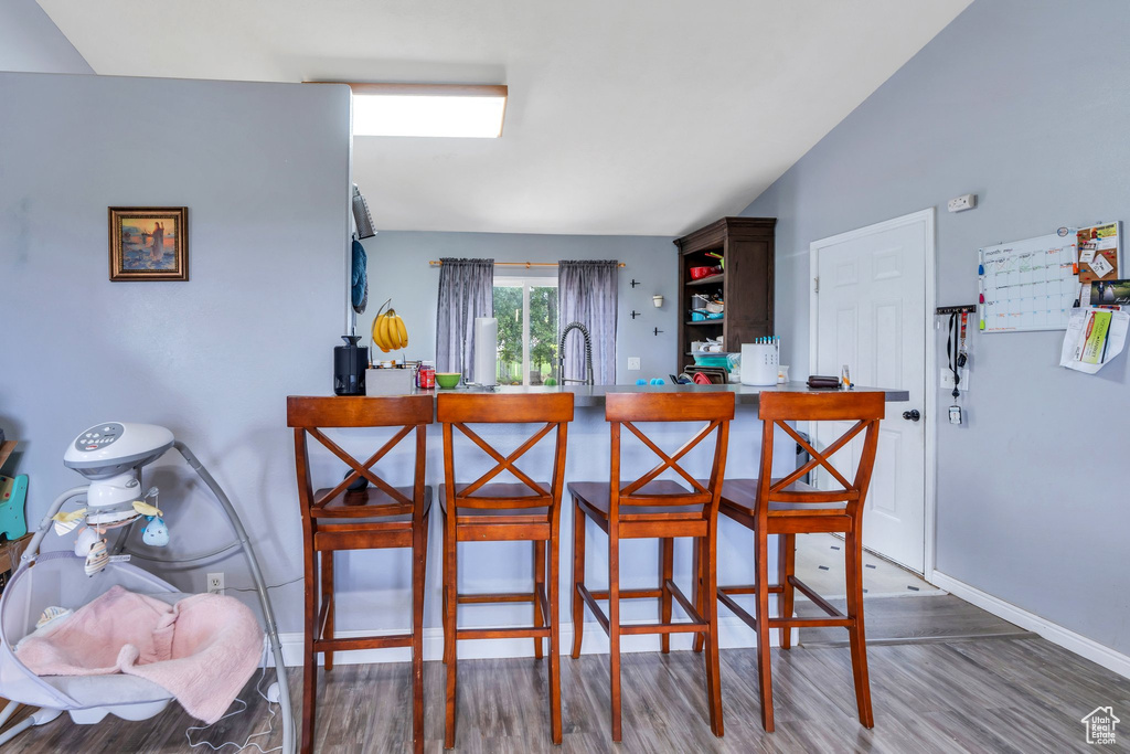Kitchen with wood finished floors, baseboards, a kitchen bar, open shelves, and a peninsula
