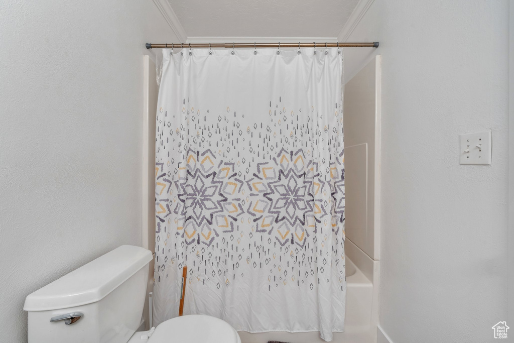 Bathroom featuring toilet, shower / bath combo, and ornamental molding