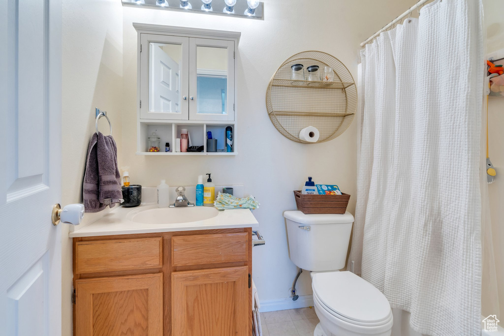 Full bath featuring toilet, vanity, a shower with shower curtain, baseboards, and tile patterned flooring