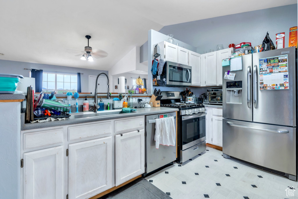 Kitchen with stainless steel appliances, light floors, a sink, a ceiling fan, and white cabinetry