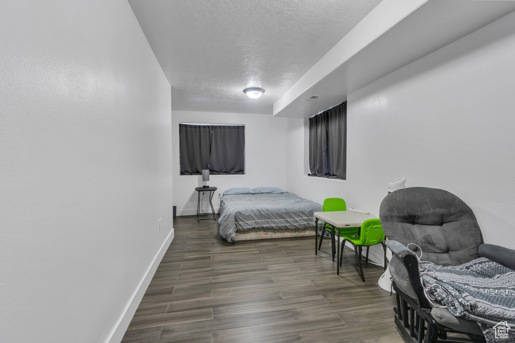 Bedroom with a textured ceiling, baseboards, and wood finished floors
