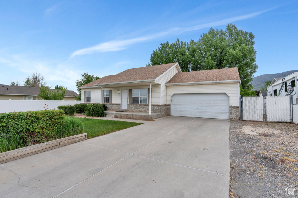Single story home with a garage, fence, driveway, and a porch