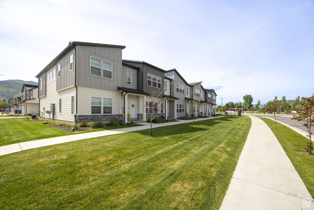 Multi unit property with board and batten siding, a front lawn, a residential view, and stone siding