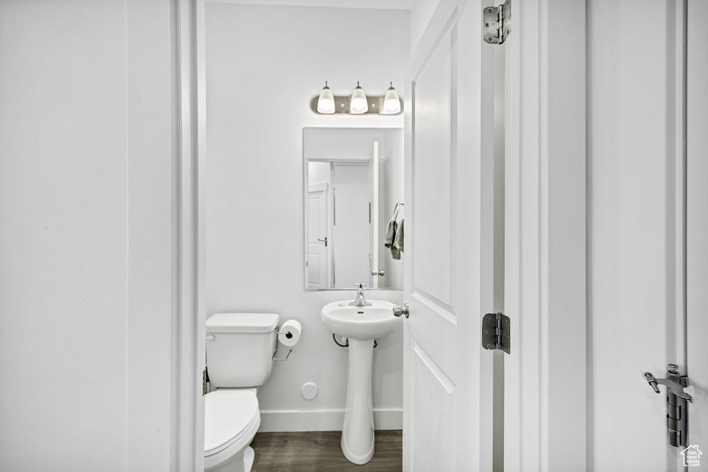 Bathroom featuring baseboards, toilet, and wood finished floors