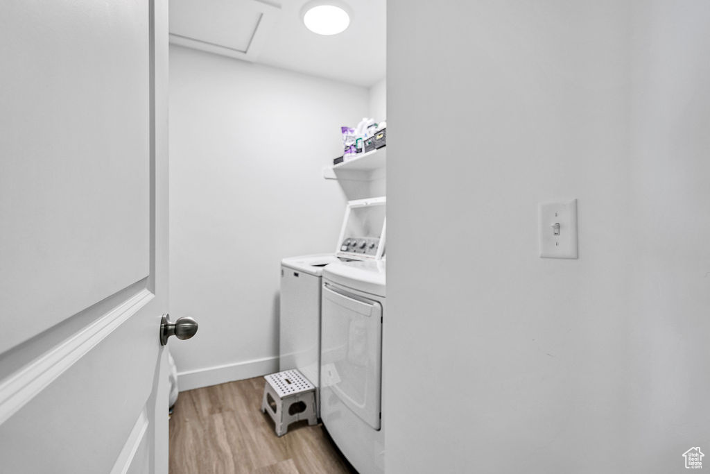 Washroom featuring washer and clothes dryer, light wood-style floors, and attic access