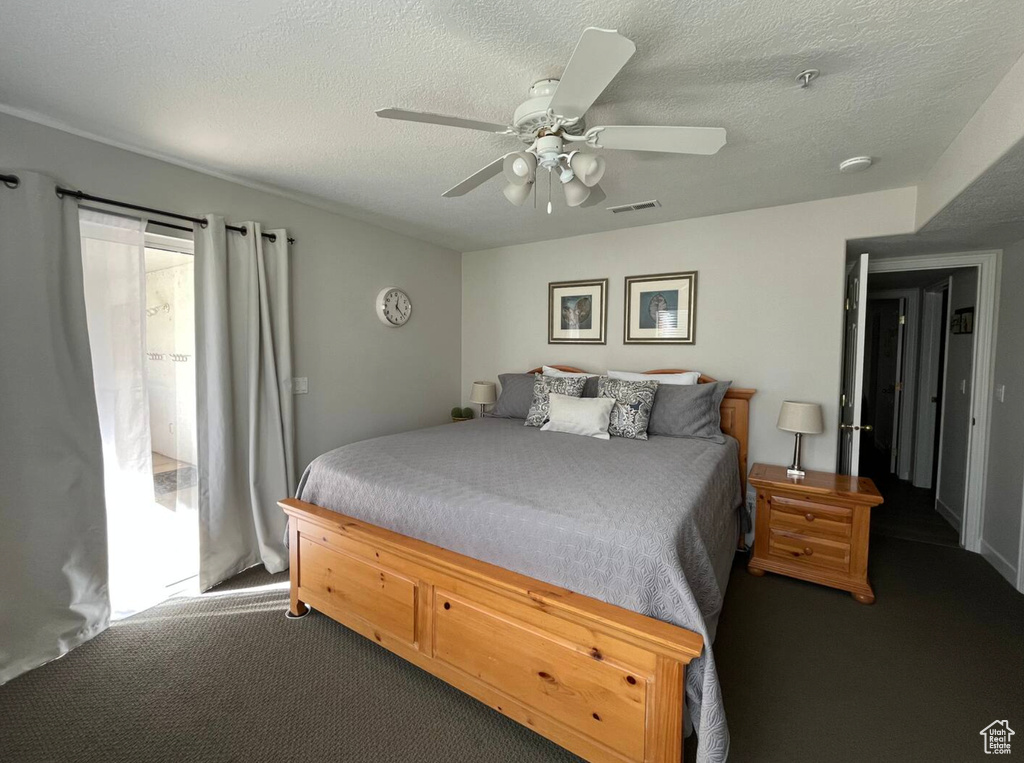 Carpeted bedroom with a ceiling fan and a textured ceiling