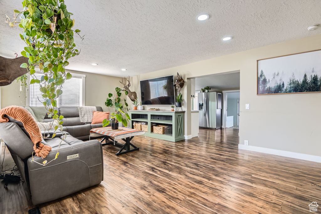 Living room featuring a textured ceiling, wood finished floors, recessed lighting, and baseboards