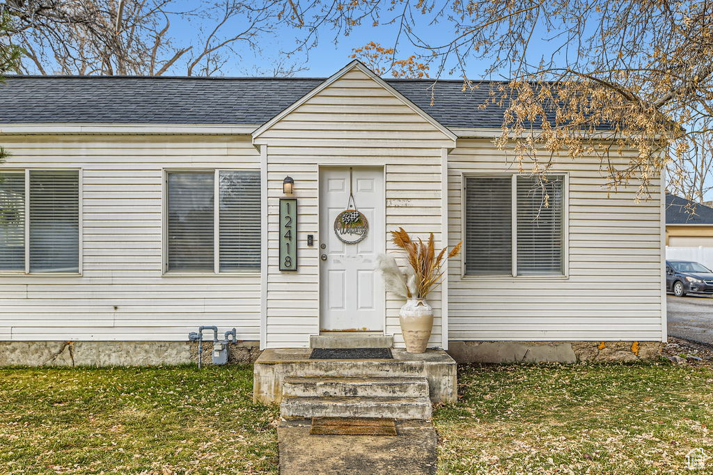 View of front of home featuring a front yard and roof with shingles