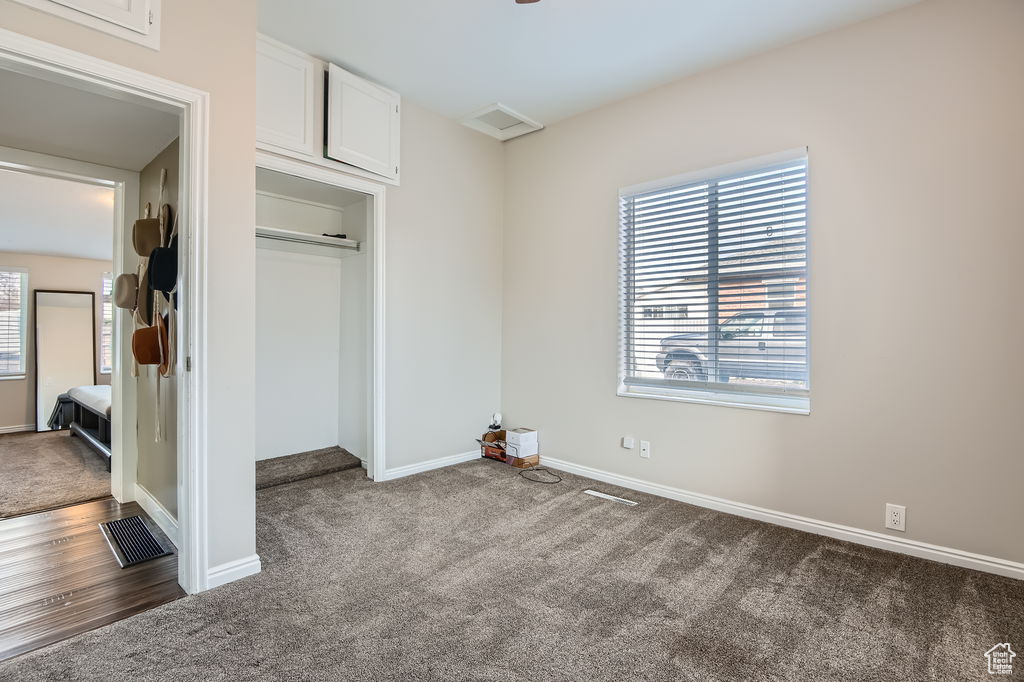 Unfurnished bedroom with dark colored carpet and baseboards