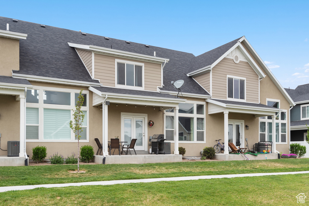 Rear view of property with a patio, a yard, and a shingled roof