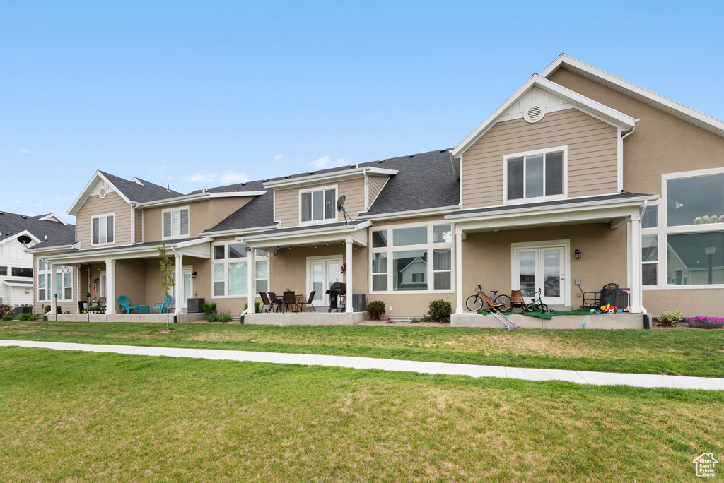 View of front of property featuring a patio, a front yard, stucco siding, french doors, and a shingled roof
