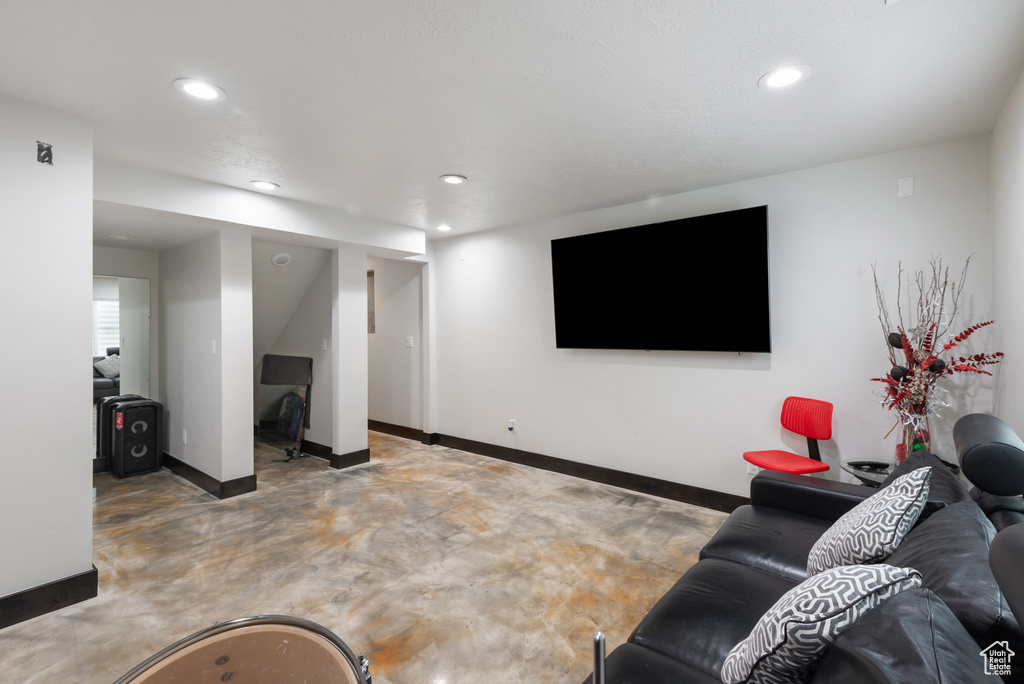 Living room with finished concrete flooring, baseboards, and recessed lighting