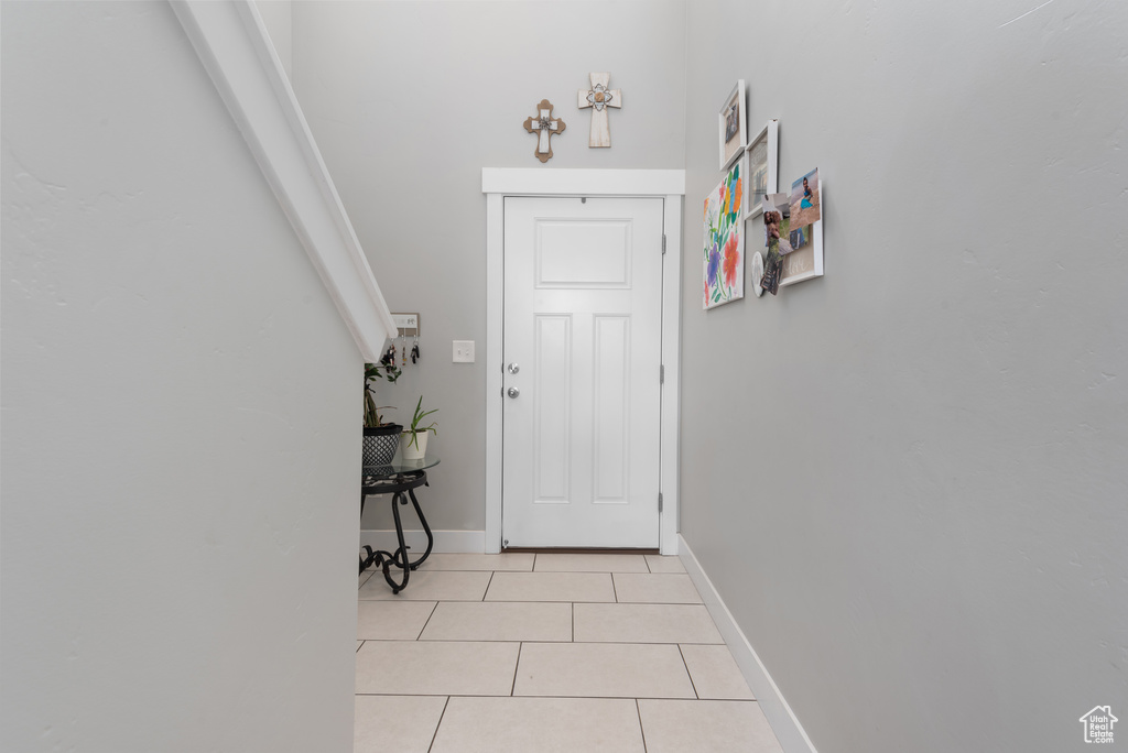 Entryway with light tile patterned flooring and baseboards