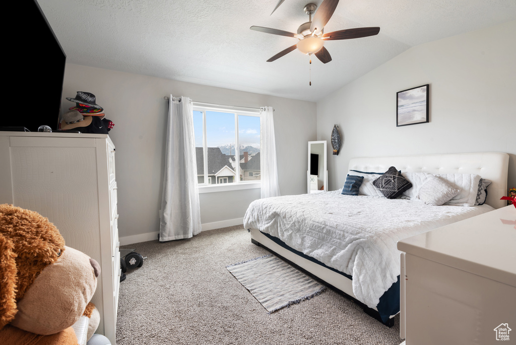 Carpeted bedroom with vaulted ceiling, baseboards, and ceiling fan