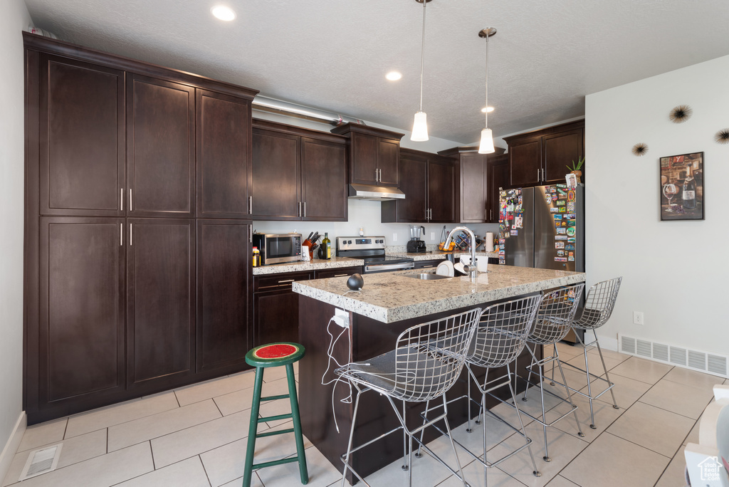 Kitchen featuring appliances with stainless steel finishes, a sink, a breakfast bar area, baseboards, and recessed lighting
