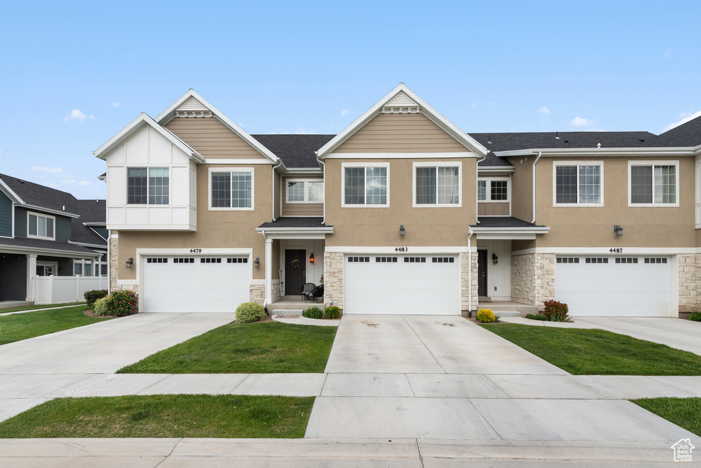 Multi unit property with stone siding, stucco siding, an attached garage, and concrete driveway