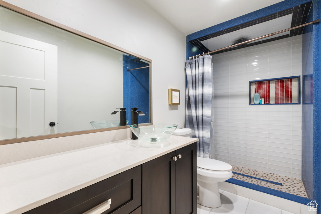 Full bath with toilet, a tile shower, vanity, and tile patterned flooring