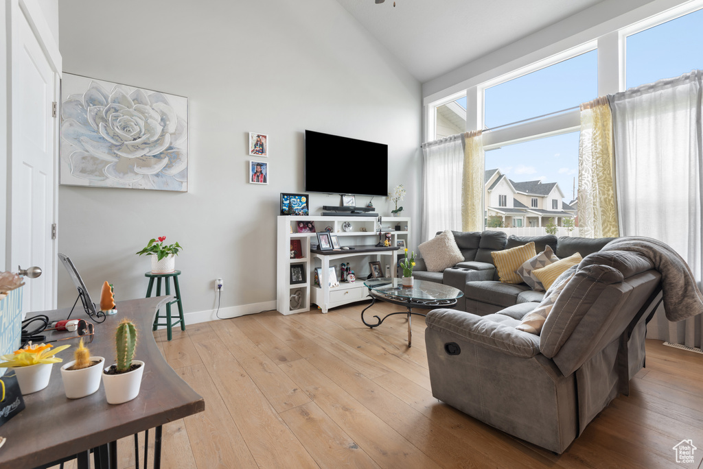 Living room featuring high vaulted ceiling, light wood-type flooring, and baseboards