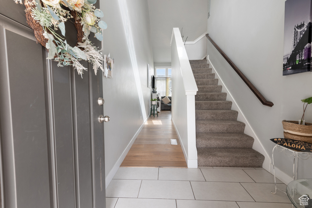 Entrance foyer with stairway, light tile patterned flooring, and baseboards