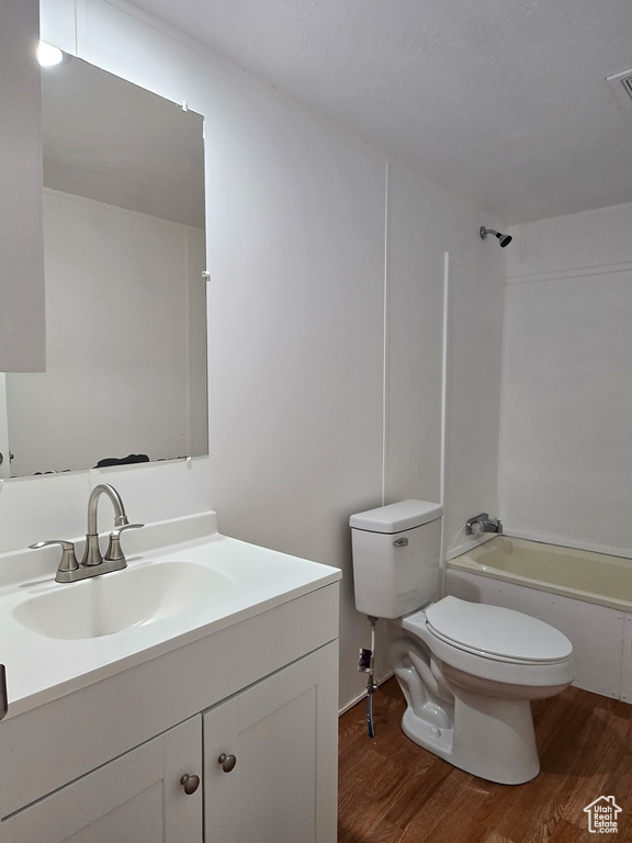 Bathroom with wood finished floors, toilet, vanity, and bathing tub / shower combination