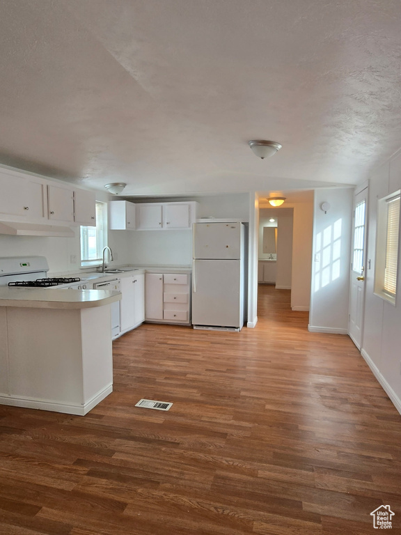 Kitchen featuring white appliances, wood finished floors, a sink, and white cabinets