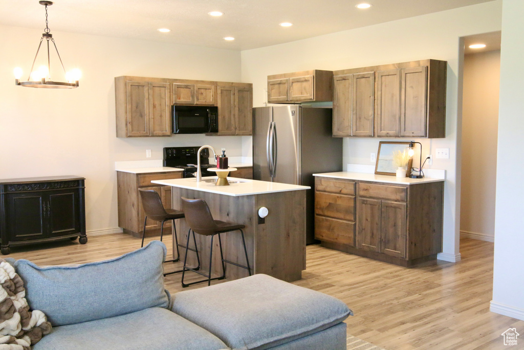 Kitchen with black appliances, open floor plan, light wood-style floors, light countertops, and recessed lighting