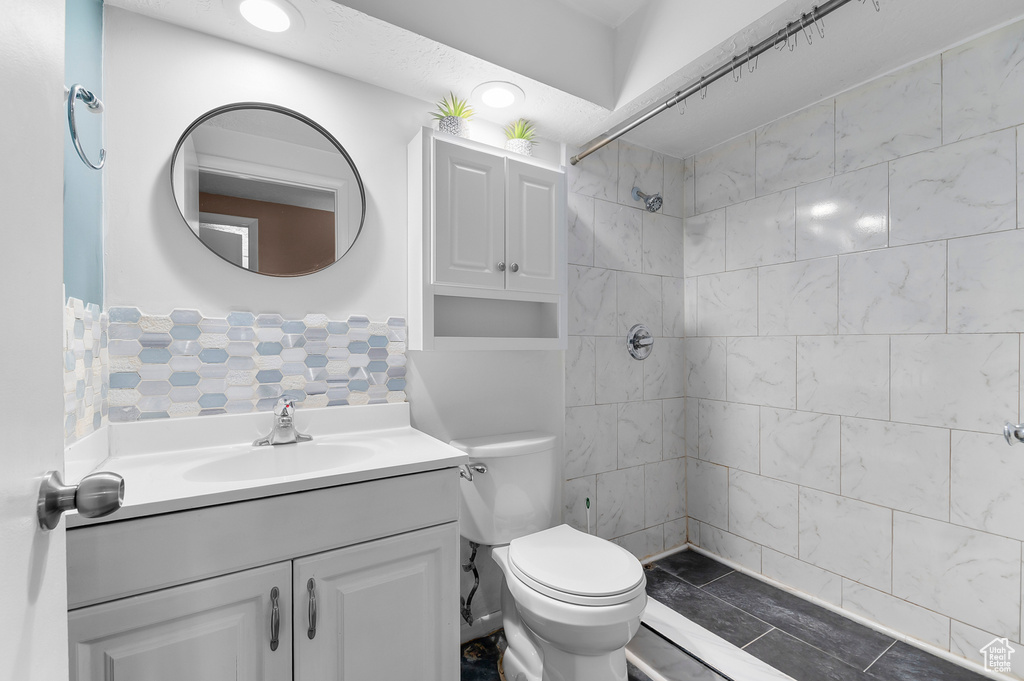 Full bathroom with vanity, a tile shower, and toilet