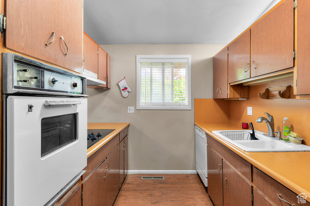 Kitchen with white appliances, a sink, light wood-style floors, and light countertops
