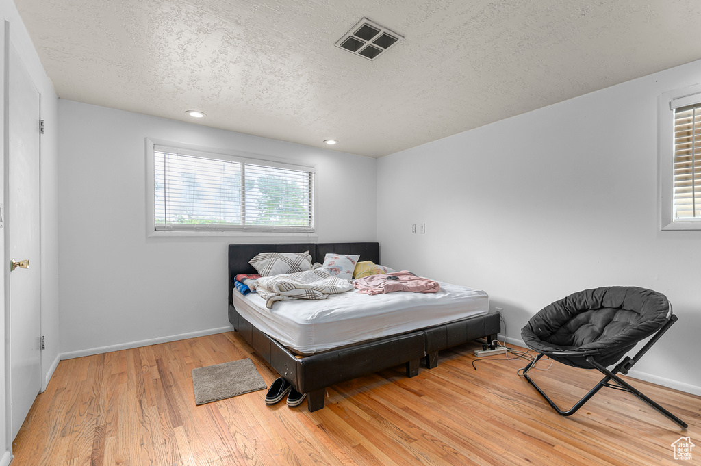 Bedroom with light wood-type flooring, a textured ceiling, baseboards, and recessed lighting
